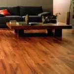 Red Teak Wooden Flooring and a short table on it, and black sofa on backside